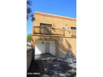 Tan two-story home with balcony and covered parking area, nestled beneath a clear blue sky at 12245 N 21St Ave # 1, Phoenix, AZ 85029