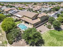 An aerial view displays a two-story home with a backyard pool and spa in a neighborhood with many other houses at 19943 E Strawberry Dr, Queen Creek, AZ 85142