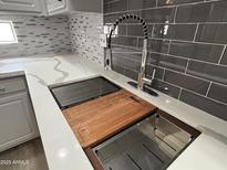 Modern kitchen sink features a stainless steel basin, cutting board, and pull-down faucet with gray subway tile backsplash at 9555 E Raintree Dr # 1055, Scottsdale, AZ 85260