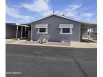 Charming gray home features awnings over the windows, desert landscaping, and a carport at 11411 N 91St Ave # 75, Peoria, AZ 85345