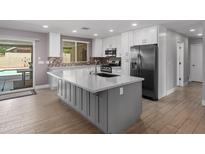 Bright, remodeled kitchen featuring white cabinets, a gray island, stainless steel appliances, and an eat-in area at 1744 E Huber St, Mesa, AZ 85203