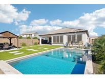 Sparkling pool surrounded by lush landscaping, covered patio, and outdoor seating at 22848 N 98Th Dr, Peoria, AZ 85383