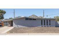 Exterior view of a single-story house with a gravel yard, gray stucco exterior, and unique vertical window accents at 2346 E Sylvia St, Phoenix, AZ 85022