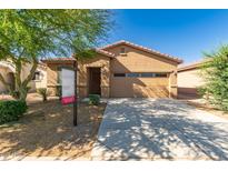 A tan single-story home with a red-tiled roof, a two-car garage, and a spacious driveway at 44188 W Cydnee Dr, Maricopa, AZ 85138