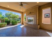 Beautiful covered patio featuring a cozy fireplace and view of the landscaped backyard and outdoor grill at 791 E Vesper Trl, Queen Creek, AZ 85140