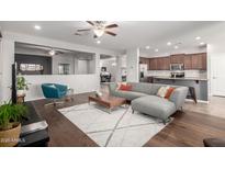 Open-concept living room showcasing the kitchen, wood floors, modern furniture, neutral colors and ceiling fans at 14921 W Luna S Dr, Litchfield Park, AZ 85340
