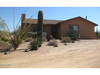A charming tan-colored home is complemented by native desert plants and gravel landscaping at 27239 N 64Th Way, Scottsdale, AZ 85266