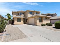 Inviting two-story home showcasing desert landscaping and a spacious concrete driveway leading to an attached two-car garage at 43860 W Roth Rd, Maricopa, AZ 85138