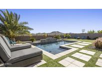 Inviting backyard pool area with stylish pavers, lush landscaping, and a tranquil waterfall feature at 537 E Balao Dr, Phoenix, AZ 85085