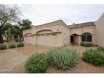 Beige single-story home showcasing a three-car garage, neutral color scheme, and desert landscaping at 8941 E Maple Dr, Scottsdale, AZ 85255