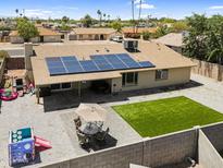 Spacious backyard with covered patio, solar panels, outdoor seating, green area, and block fence at 12447 N 50Th Ln, Glendale, AZ 85304