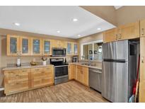 Bright kitchen featuring stainless steel appliances, light wood cabinets, and tile flooring at 12447 N 50Th Ln, Glendale, AZ 85304