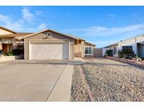 Single-story home showcasing a beige exterior, two car garage, and low maintenance rock landscaping at 23829 N 36Th Dr, Glendale, AZ 85310