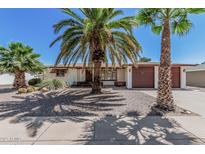 Charming single-story home featuring desert landscaping with mature palm trees and a two-car garage at 5625 E Dodge St, Mesa, AZ 85205
