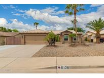 Charming home features a two-car garage, desert landscaping, and a tile roof at 6128 E Portia St, Mesa, AZ 85215