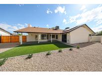 View of the backyard with a covered patio, gravel landscaping, and green turf at 6228 E Blanche Dr, Scottsdale, AZ 85254