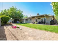 Expansive backyard with lush grass, a gravel area, and a covered patio with seating at 8313 E Camelback Rd, Scottsdale, AZ 85251