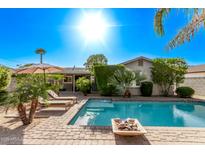 Relaxing backyard pool area featuring a brick surround, lounge chairs, and lush greenery under a bright, sunny sky at 3323 N 28Th St, Phoenix, AZ 85016