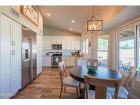Bright kitchen with white cabinetry, stainless steel appliances, and a cozy dining area near the window at 11447 N 109Th St, Scottsdale, AZ 85259