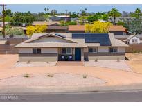 Charming single-story home featuring desert landscaping, solar panels, and a cozy front patio at 6502 E Rustic Dr, Mesa, AZ 85215