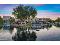 Waterfront homes feature manicured lawns, boat docks, and picturesque reflections on the serene lake, at sunset at 1267 E Chicago Cir, Chandler, AZ 85225