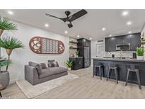 Open-concept living room features a plush gray sofa, unique wall art, and a modern kitchen bar at 5995 N 78Th St # 2078, Scottsdale, AZ 85250