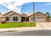 Charming single-story home with a well-manicured lawn, desert landscaping, and a two-car garage at 6577 W Abraham Ln, Glendale, AZ 85308