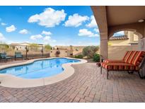 Inviting pool area with a lounge chair on a brick patio, surrounded by desert landscaping at 13648 W Jesse Red Dr, Peoria, AZ 85383