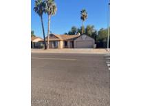 Single-story home with a two-car garage and palm trees in the front yard, under a clear blue sky at 5219 W Eugie Ave, Glendale, AZ 85304