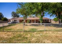 Charming single-story home featuring a chain-link fence, mature trees and a well-maintained lawn at 11422 W Hidalgo Ave, Tolleson, AZ 85353