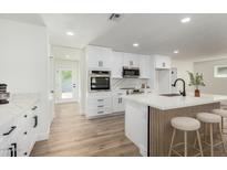 Modern white kitchen boasts stainless steel appliances, a marble backsplash, and a stylish kitchen island at 1313 N 71St St, Scottsdale, AZ 85257