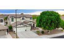 Charming two-story home with a three-car garage and a well-manicured lawn with stone accents and desert landscaping at 14823 W Windsor Ave, Goodyear, AZ 85395
