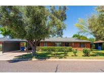 Charming brick home featuring mature trees, a covered carport, and well-maintained landscaping at 2908 E Pinchot Ave, Phoenix, AZ 85016