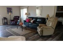 Spacious living room featuring hardwood floors, stylish sofas and a decorative area rug at 43914 W Wade Dr, Maricopa, AZ 85138