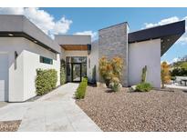 Modern home exterior with desert landscaping, a stone facade, and a sleek design, creating a stylish curb appeal at 4502 E Solano Dr, Phoenix, AZ 85018