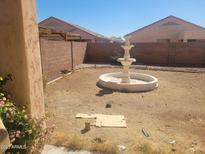 Spacious backyard featuring a decorative fountain, surrounded by a block wall for added privacy at 5665 W Laurie Ln, Glendale, AZ 85302