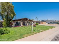 Charming single-story home featuring a well-manicured lawn and inviting porch with flowers and a table set at 6244 W Clouse Dr, Phoenix, AZ 85033