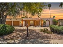 Charming home exterior featuring a tiled roof portico, desert landscaping, and two-car garage at 6611 E Voltaire Ave, Scottsdale, AZ 85254