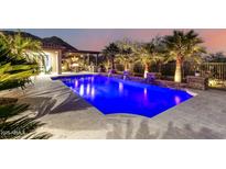 Beautiful backyard pool with water features, mature landscaping, and outdoor kitchen area at twilight at 16201 S 29Th Ave, Phoenix, AZ 85045