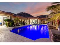 Expansive backyard features a dazzling pool, covered patio, outdoor seating, and stunning mountain views at dusk at 16201 S 29Th Ave, Phoenix, AZ 85045