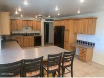 A spacious kitchen features wooden cabinets, a tiled floor, and a long center island with bar stool seating at 207 E Papago Dr, Tempe, AZ 85288