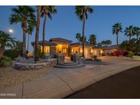 Inviting home featuring meticulous landscaping, stone accents and palm trees, set in a serene, well-lit neighborhood at 19541 N Rim Dr, Surprise, AZ 85374