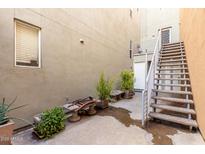 Exterior shot featuring a wooden staircase, potted plants, bench seating, and a textured neutral wall at 706 E Washington St # 207, Phoenix, AZ 85034