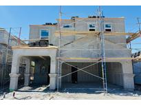 Unfinished two-story home with stacked roofing tiles and scaffolding at construction site on a sunny day at 5041 E Umber Rd, San Tan Valley, AZ 85143
