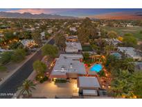 Expansive aerial view showcasing a Scottsdale home with a sparkling pool, lush landscaping, and mountain views at sunset at 5837 E Presidio Rd, Scottsdale, AZ 85254