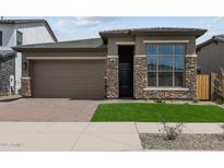 Beautiful single-Gathering home with a two-car garage, stone accents, green grass and a paver driveway at 22762 E Stacey Rd, Queen Creek, AZ 85142