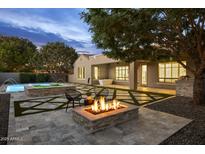 Relaxing backyard featuring a stone fire pit, lush landscaping, and a tranquil pool with fountains at 4300 S Marble St, Gilbert, AZ 85297