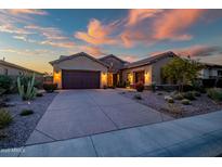 Charming single-Gathering home featuring desert landscaping, an attached garage, and warm exterior lighting at dusk at 30224 N 52Nd Pl, Cave Creek, AZ 85331