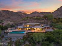 Stunning modern home featuring a pool, outdoor seating, and beautiful desert landscaping at sunset at 4536 E Foothill Dr, Paradise Valley, AZ 85253