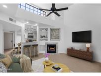 Bright living room featuring vaulted ceilings, fan, fireplace, and an open view of the bar and kitchen at 1126 W Elliot Rd # 2040, Chandler, AZ 85224